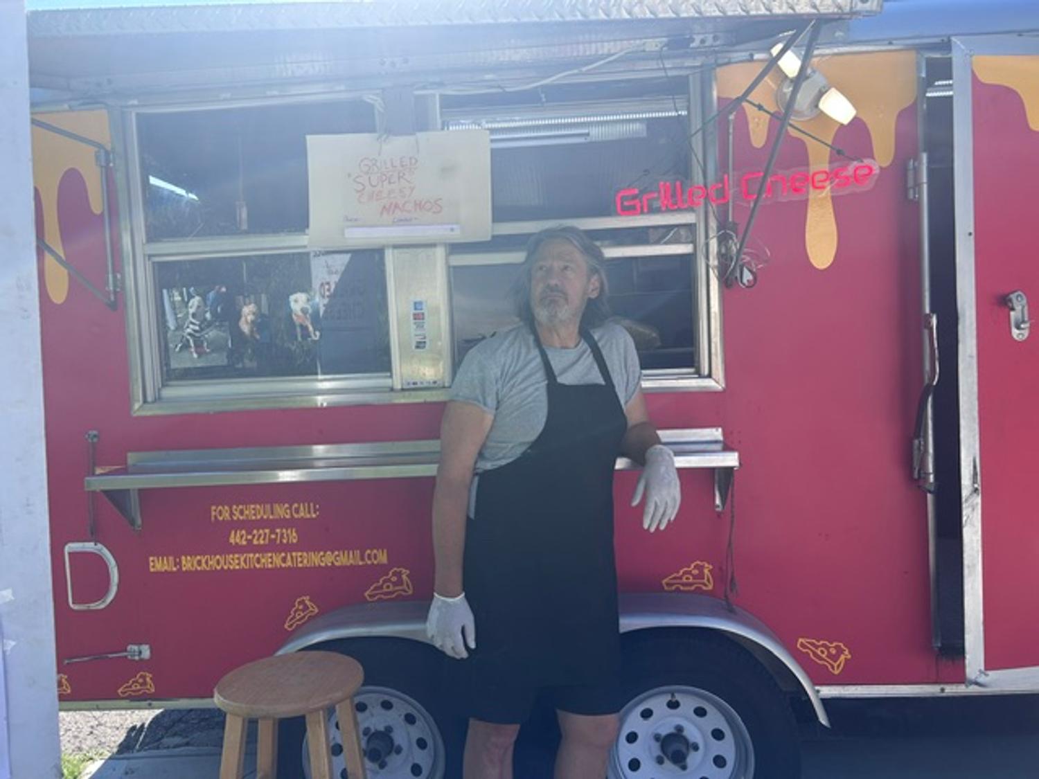 Our chef outside the trailer beside the grilled super cheesy nachos sign