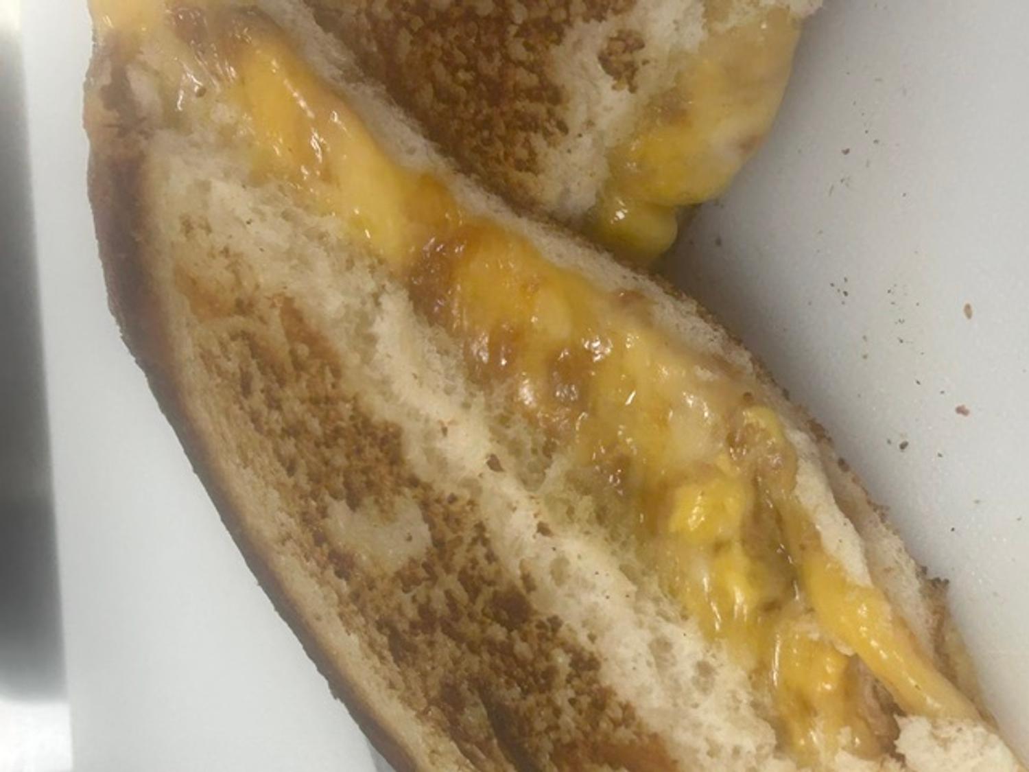 Close-up of a golden griddled grilled cheese with melted cheese pulling apart