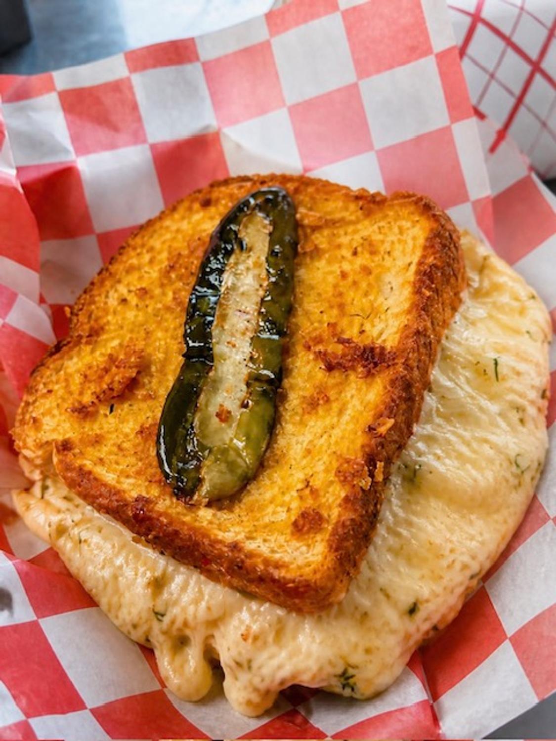 The Dill Pickle grilled cheese with a crisp pickle spear and cheese crisped over the edges