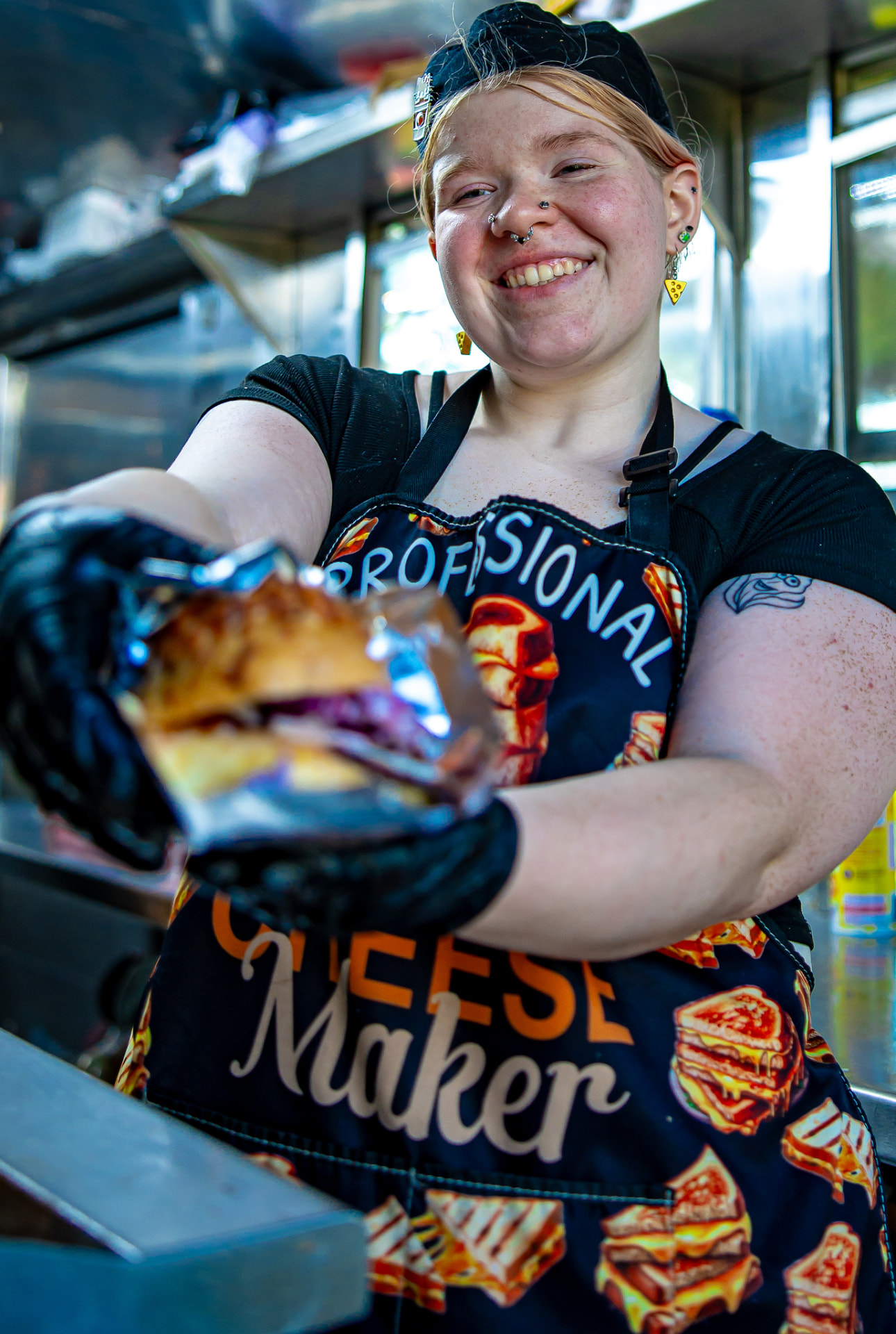 Our cook in a Professional Cheese Maker apron handing over a fresh gourmet grilled cheese