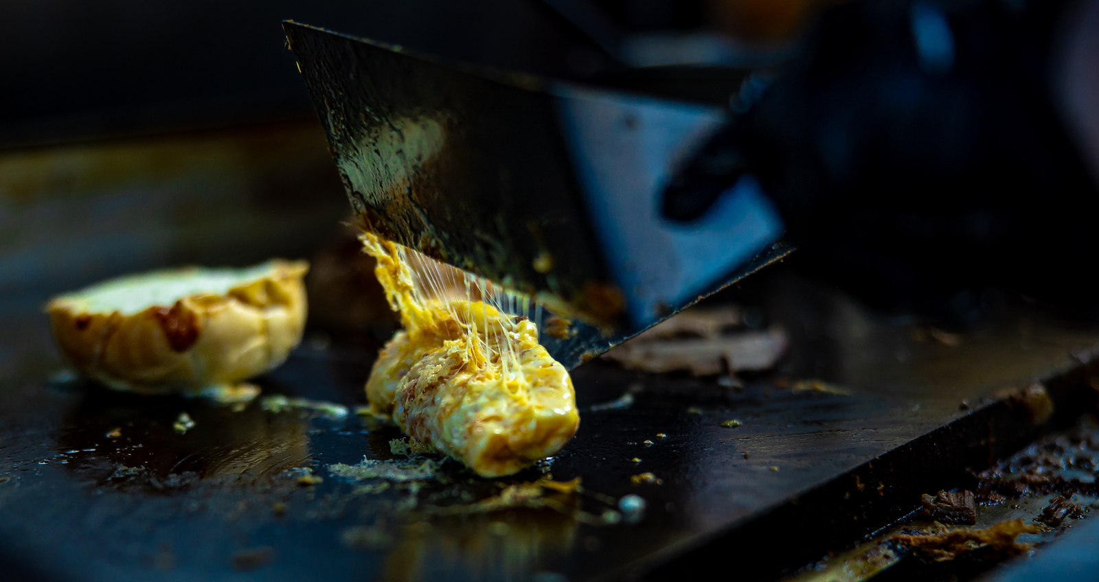 Melted cheese stretching from the spatula on the griddle